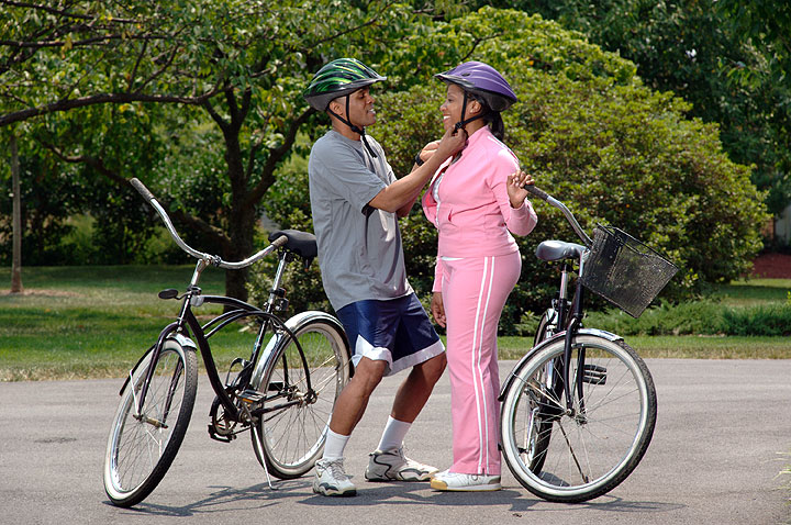 Man and woman putting on bicycle helmets, preparing for bike ride